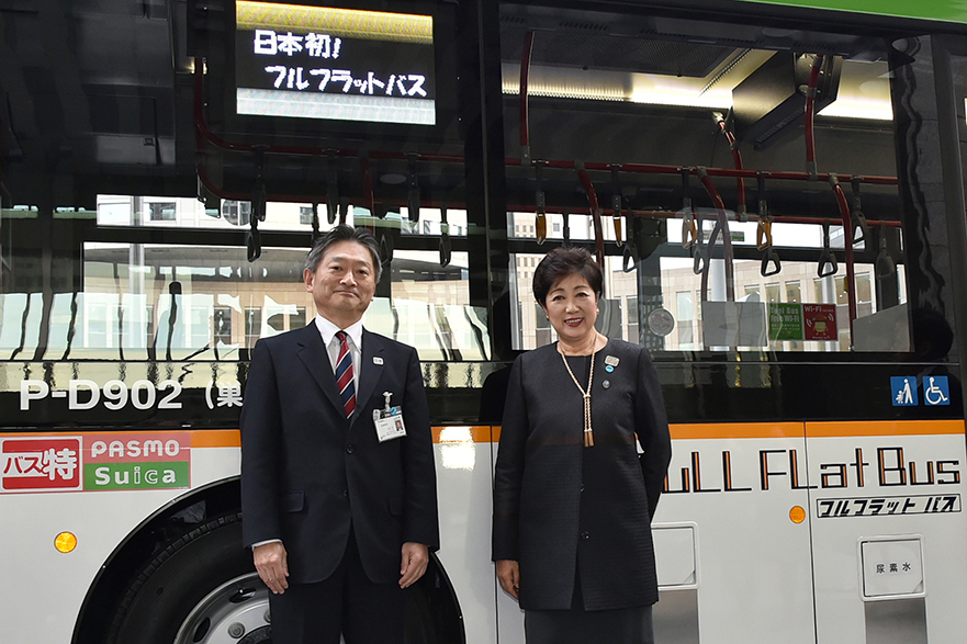Governor Koike stands in front of the first fully flat floor bus to operate in Japan