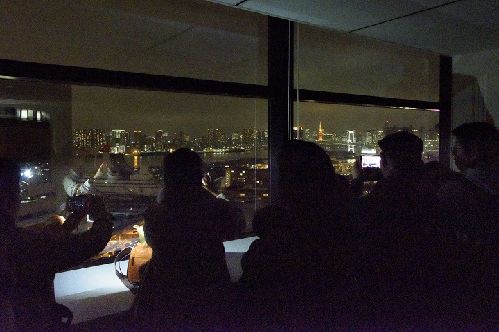 東京臨海部広報展示室から夜景を眺める参加者の写真
